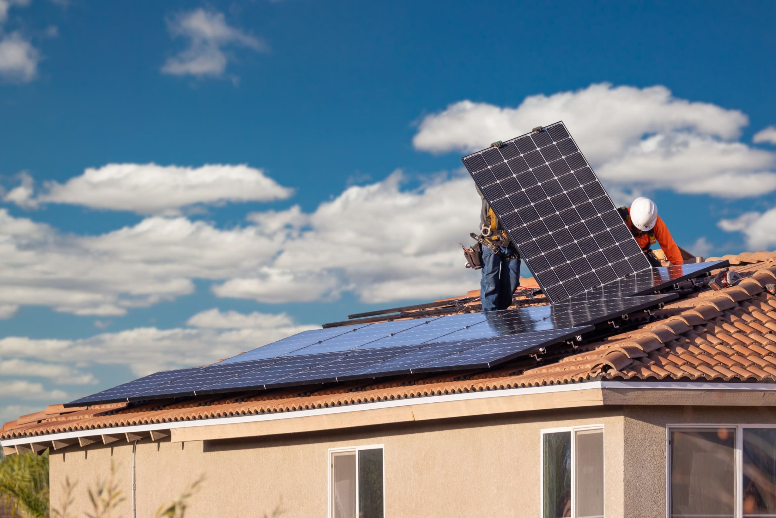Trabalhadores instalando um painel de energia solar fotovoltaica em um telhado de uma casa